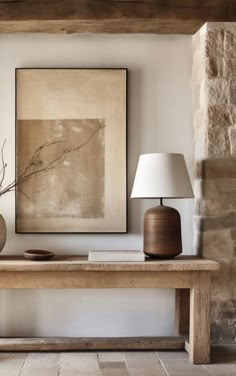 a table with two vases and a lamp on it in front of a painting