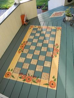 a wooden deck with flowers painted on it and potted plants next to the door