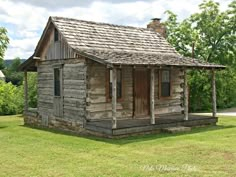 an old log cabin sits in the grass