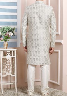 Ready-Made Sherwani With Trouser. Jacquard Brocade Fabric Top. Art Dupion Churidar Ready Made Trouser. Crafted in Chinese Collar Neck, and Full Sleeve. Satin Lining with Plain Work. High-Quality Matching Buttons. Please Note: The footwear shown in the picture is for presentation and photography purpose only. Color: There might be slight color variation due to lightings and flashes while photo shooting. The color may also vary because of different screen resolutions. Wash Care: Dry Clean Only. Designer Brocade Bandhgala With Chikankari Embroidery, Designer Brocade Sherwani With Chikankari Embroidery, Eid Brocade Bandhgala With Chikankari Embroidery, Eid Bandhgala With Chikankari Embroidery In Brocade, Elegant Art Silk Bandhgala With Chikankari Embroidery, Silver Kurta With Zari Work For Wedding, Brocade Sherwani With Naqshi For Diwali, Silver Wedding Kurta With Zari Work, Traditional Silver Kurta With Resham Embroidery