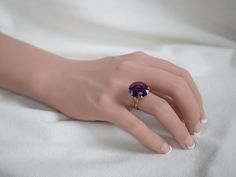 This setting is a true classic! Considered the height of fashion in the Mid Century era, the lines of this simple solitaire are clean and well balanced, providing a sophisticated look! We've set this vintage setting with a gorgeous amethyst. A deep regal purple hue, this sparkling stone glitters with intense fire from every facet.Metal: 18K Yellow GoldGem: Amethyst 10.11 CaratsGem Measurements: 17.1 x 14.9 mm, OvalRing Size: 7.50Marks: “18K” Stamped on the inside band