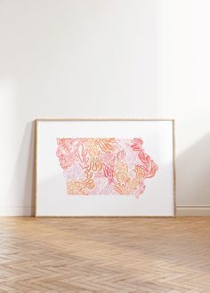 an art print is hanging on the wall next to a wooden floor and white walls