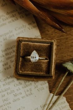 an engagement ring sitting in a box on top of a piece of paper