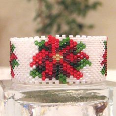 a close up of a beaded bracelet with poinsettis and leaves on it