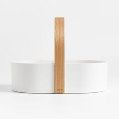 a white bowl with a wooden stand in front of it on a white surface,