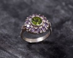 Peridot Ring set with Natural Peridot in a diamond cut & natural green color, at size 7mm together with Natural Amethyst at size 3mm each (2.3 Cts combined) from Brazil.Solid 925 Sterling Silver ☞ made to last.Click here for ☞ Matching PendantClick here for ☞ Matching EarringsClick here for ☞ Flower Collection Details:• Natural Peridot & Amethyst sourced from Brazil• Peridot: 7mm, 1.3 Cts, diamond cut• Amethyst: 3mm each, 1 Ct total, diamond cut• Dimensions: Band width ≈ 2.3mm, thickness ≈ 1.3mm• Solid 925 Sterling Silver❀ Each Natural Gem is unique & will have Slight variations from the product pictures "no two Natural Stones are alike"SKU 2243 Victorian Ring, Silver Ring Designs, Vintage Silver Rings, Flower Collection, Victorian Rings, Peridot Ring, Product Pictures, Flower Ring, Amethyst Ring