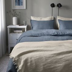 a bed with blue sheets and pillows in a bedroom