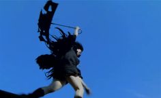 a woman flying through the air while holding onto an umbrella in front of a blue sky