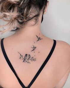 the back of a woman's neck with birds and flowers tattoo on her left shoulder