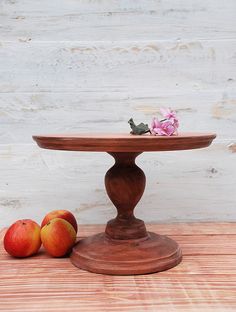 two apples sitting on top of a wooden table next to an apple slice and flower