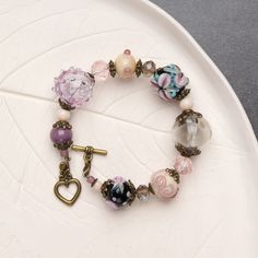 "This chunky boho bracelet features beautiful purple flowers and intricate floral details. It's the perfect addition to any bohemian-inspired outfit, adding a touch of charm and elegance. The chunky design of the bracelet makes it a statement piece that is sure to get noticed.  💕 You will definitely look stunning with this cute beaded bracelet! 👉 Please note that this bracelet has a fixed size and is designed to fit a wrist circumference of 15.5-16.5cm (6.1\"- 6.5\" inches). If you require a s Bohemian Charm Bracelet Bangle With Colorful Beads, Bohemian Style Stretch Bracelet Gift, Vintage Pink Bracelets With Round Beads, Purple Bohemian Beaded Bracelets As Gift, Pink Bohemian Charm Bracelet With Round Beads, Bohemian Pink Charm Bracelet With Round Beads, Handmade Purple Stretch Bracelet, Handmade Purple Bohemian Beaded Bracelets, Bohemian Flower Beaded Bracelets For Festival