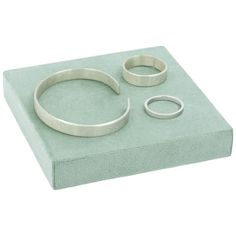 a set of three silver rings sitting on top of a green box