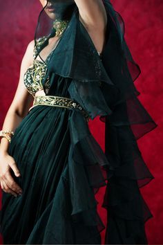 Introducing the stunning Lara Ruffle Saree – a true masterpiece of traditional Indian design and modern sophistication! This beautiful saree features a dark green chiffon and organza ruffled pre-draped saree, paired with a hand-embroidered blouse and waist belt.
The intricate hand embroidery on the blouse and waist belt showcases the impeccable craftsmanship and attention to detail that goes into every piece. The flowing chiffon and organza fabric of the saree creates a sense of grace and moveme Pre Draped Saree, Saree Chiffon, Hand Embroidered Blouse, Draped Saree, Add Sleeves, Ruffle Saree, Drape Saree, Green Saree, Organza Saree