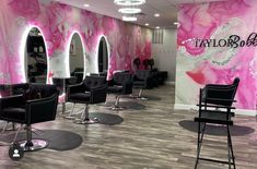 the salon is decorated with pink and white marbled walls, black chairs, and mirrors