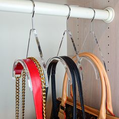 two purses are hanging from hooks on a coat rack with chains attached to them