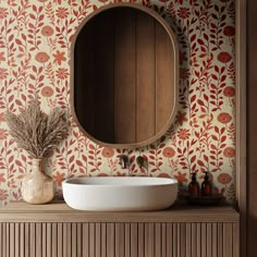 a round mirror on the wall above a sink in a room with floral wallpaper