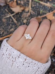 a woman's hand wearing a ring with flowers on the middle of her finger