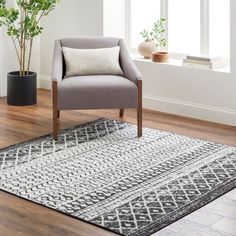 a gray chair sitting on top of a wooden floor next to a potted plant