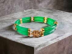 Our 'Double Fu Fuku Fortune Jade Bracelet' embodies radiance and stature, with hand carved jade lengths intertwined with 14K Gold; a unisex statement. The two layers of cylindrical Jade tubes stands for courage and strength.   Our top craftsman signs off the piece with a crafted symbol of fortune at the clasp. The Han symbol for fortune and luck evokes an unrivaled sense of positivity and happiness.  Materials: 3.00g 14K Gold and 16.40g Jadeite (Approximately) Dimensions: 185 x 10 x 8 mm Gross W Luxury Jade Jewelry, Luxury Jade Bracelets For Formal Occasions, Luxury Formal Jade Bracelets, Luxury Gold Jade Bracelets, Chinese Bracelet, Purple Vase, Jade Dragon, Purple Jade, Carved Jade