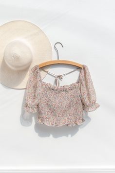 A sweet and simple versatile wardrobe staple perfect for summer, the Emily cropped blouse features a smocked elastic bodice, short sleeves with smocked cuffs, a cropped hem, and a pretty floral-print chiffon. Please Note- This item is final sale only. . Details: S: Bust 34", Length 18" M: Bust 36", Length 18.5" L: Bust 38", Length 19" Length Measured from Shoulder Unlined Material: 100% Polyester Facing: 100% Rayon Imported Gentle Wash Cold / Line Dry Feminine Floral Print Smocked Top For Summer, Feminine Summer Smocked Top With Floral Print, Feminine Floral Smocked Top For Summer, Summer Feminine Floral Print Smocked Top, Summer Cropped Smocked Bodice Crop Top, Summer Crop Top With Smocked Bodice, Summer Vacation Crop Top With Smocked Bodice, Summer Crop Top With Smocked Bodice For Day Out, Short Sleeve Smocked Top With Smocked Cuffs For Brunch