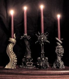 four candles are lined up in a row with skulls and crosses around them on the table