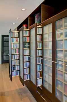 there are many bookshelves in the room with glass doors on each side and shelves full of dvds