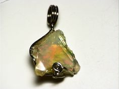 This pendant features a raw, uncut Ethiopian opal. The stone weighs in at 6.5 carats, and measures 0.65 x 0.66 inches (16.6 x 16.8 mm) Ethiopian hydrophane opal is really exciting material. Since its discovery in 2008, it has provided very stable and beautiful stones with such rich and varied color as to rival the best of Australia. Ranging from black to white, with fire spanning the entire rainbow, just about every taste is catered to by this find. This is a really beautiful piece. It has a lig Unique Raw Jewelry For Gifts, Elegant Raw Jewelry Gift, Elegant Raw Jewelry For Gifts, Ethiopian Opal Gemstone Jewelry As Gift, Ethiopian Opal Gemstone Jewelry For Gifts, Ethiopian Opal Jewelry With Natural Stones As Gift, Unique Ethiopian Opal Gemstone Jewelry, Fusion Style Opal Gemstone Jewelry, Gift Jewelry With Ethiopian Opal And Natural Stones