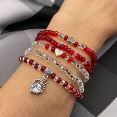 a woman's arm with four bracelets and a heart charm on the wrist