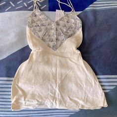 a white dress with silver sequins on it laying on a blue and white blanket