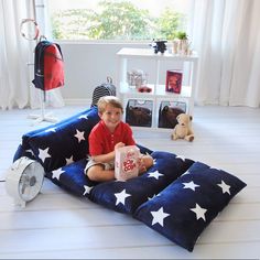 a young boy sitting on top of a blue pillow