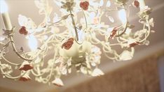 a chandelier with roses hanging from it's arms and lights on the ceiling