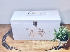 a white box sitting on top of a wooden table next to a potted plant