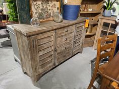 an old wooden cabinet with drawers and vases on it in a room filled with furniture