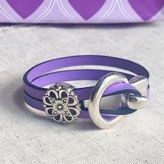 a purple leather bracelet with a silver flower on it