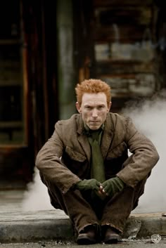 a man with red hair sitting on the ground