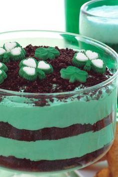 a cake with green frosting and shamrocks on top is in a glass dish