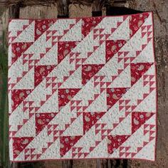 a red and white quilt hanging from a tree