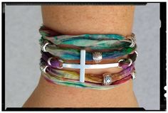 a woman's arm with three different bracelets and a white cross on it