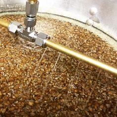 a large metal bowl filled with lots of brown grains and a machine working on it's side