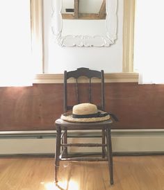 a wooden chair with a straw hat on it in front of a mirror and wall