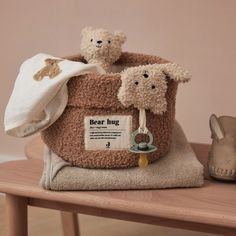 two teddy bears sitting in a bag on top of a wooden table next to shoes