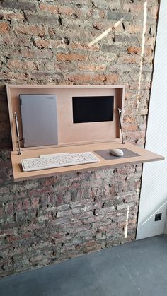 a wooden desk with a keyboard and mouse on it next to a wall mounted monitor