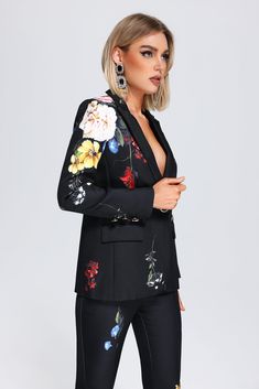 a woman is wearing a black suit with flowers on it and has her arms crossed