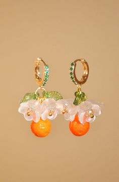 "Positano flower and orange hoop earrings, glass clementine drop earrings, food earrings, fruit earrings, gold summer custom earrings Inspired by Positano in Italy, these lovely little earrings are perfect for giving your outfit a taste of summer. The hoop is a 24k gold-plated earring, studded with small green zircons. Hanging from the hoop are pretty Czech crystal white flowers, green leaves, and at the bottom, an orange, also made of Czech crystal. Floral and fruity, these earrings smell like Summer Orange Flower-shaped Jewelry, Orange Flower-shaped Earrings For Summer, Orange Flower Shaped Earrings For Summer, Summer Orange Drop Earrings, Orange Dangle Flower Earrings With Ear Wire, Summer Orange Jewelry With Fruit Design, Orange Fruit Design Earrings As Gift, Smell Like Summer, Matching Necklace And Bracelet