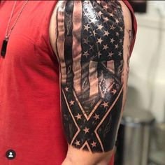 a man's arm with an american flag and cross tattoo on the left shoulder