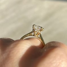 a close up of a person's hand holding a ring with a diamond on it