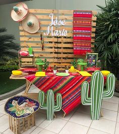 a colorful table with cactus decorations and hats on it's head stands in front of a wooden sign that says jose maria