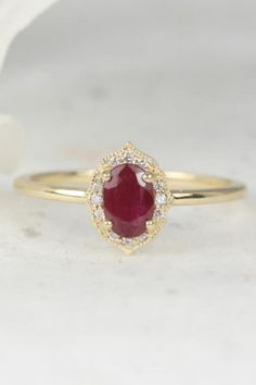 This stunning Mae ring features a gorgeous ruby center stone and conflict-free diamonds.   #ruby #conflictfreediamonds #yellowgoldring #maering Elegant Formal Ruby Halo Ring, Elegant Ruby Ring With Bezel Setting For Wedding, Elegant Ruby Ring With Halo Setting For Promise, Elegant Bezel-set Ruby Wedding Ring, Elegant Ruby Ring With Halo Setting For Gift, Elegant Ruby Halo Promise Ring, Exquisite Oval Ruby Ring For Wedding, Exquisite Oval Ruby Wedding Ring, Elegant Ruby Halo Ring