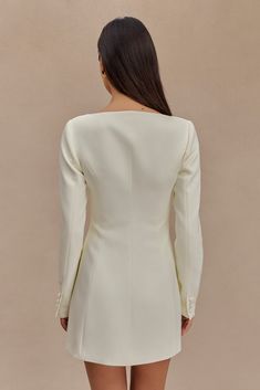 the back of a woman's body wearing a white blazer and short shorts