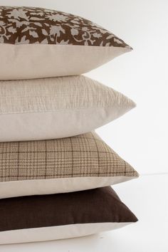 four pillows stacked on top of each other in different colors and patterns, one is brown